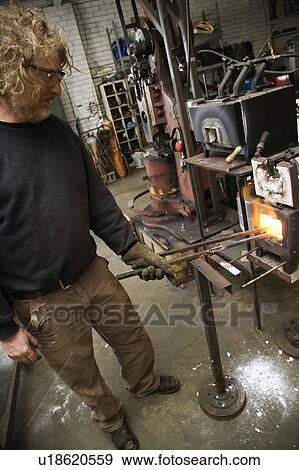 Stock Photo - Metal-smith heating metal in forge. Fotosearch
