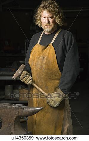 Metalsmith holding hammer with stern expression. View Large Photo Image Stock Photo - Metalsmith holding hammer with stern expression.. Fotosearch