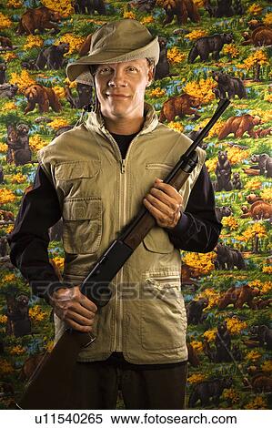 Mid-adult male holding a rifle. View Large Photo Image Stock Photography - Mid-adult male holding a rifle.. Fotosearch