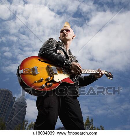 Stock Photo - Portrait of male punk holding guitar with skyline in background. Fotosearch