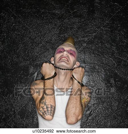 Stock Image - Punk holding handcuffs beneath chin. Fotosearch