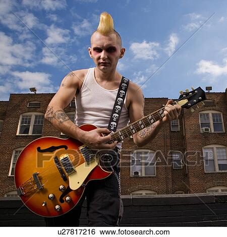 Stock Photograph - Punk playing guitar with building in background. Fotosearch