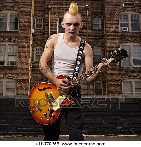 Stock Photography - Punk playing guitar with building in background. Fotosearch