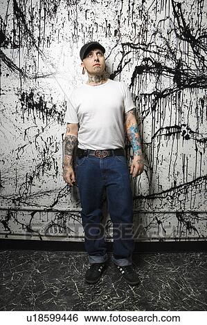 Tattooed and pierced man standing against paint splattered background View Large Photo Image Stock Photograph - Tattooed and pierced man standing against paint splattered background. Fotosearch