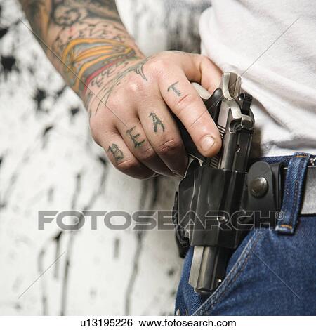 Stock Photograph - Tattooed man wearing holster with gun. Fotosearch