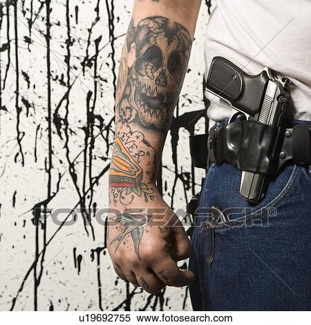 Stock Photography - Tattooed man wearing holster with gun. Fotosearch