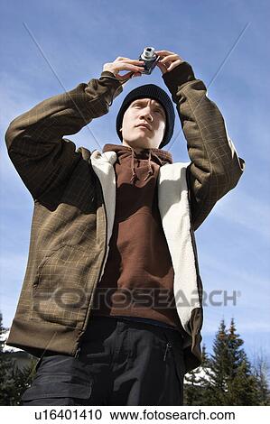 Stock Image - Teenager taking a picture with a digital camera. Fotosearch