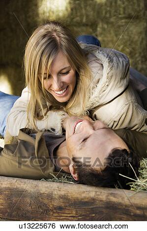 Stock Photograph - Adult couple laying in hay. Fotosearch