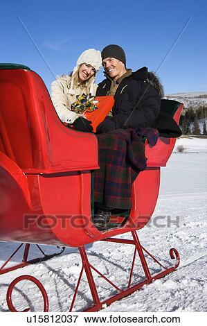 Couple in sleigh holding a present View Large Photo Image Stock Photo - Couple in sleigh holding a present . Fotosearch