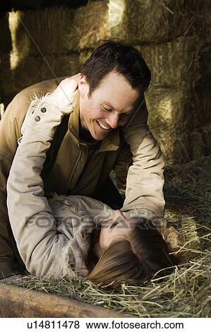 Stock Photo - Couple laying in hay embracing. Fotosearch