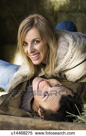 Stock Photography - Couple lying in hay and smiling up at viewer. Fotosearch