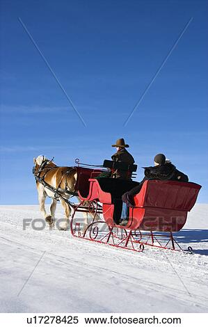 Stock Photography - Man driving horse drawn sleigh with couple in back. Fotosearch