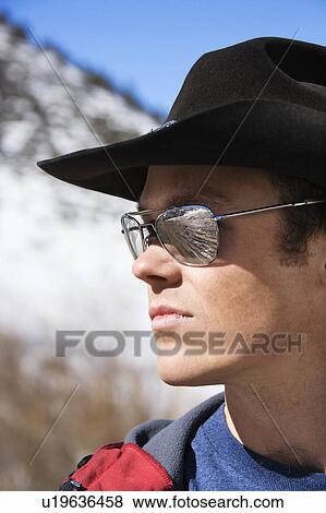 Stock Photo - Mid-adult man wearing sunglasses and cowboy hat. Fotosearch