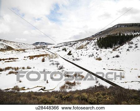 Railroad tracks in snow covered landscape leading towards small town View Large Photo Image Stock Photograph - Railroad tracks in snow covered landscape leading towards small town. Fotosearch