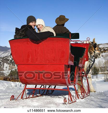 Rear view of man driving horse drawn sleigh with couple looking back at viewer. View Large Photo Image Stock Image - Rear view of man driving horse drawn sleigh with couple looking back at viewer.. Fotosearch