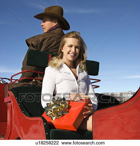 Stock Image - Woman holding present in sleigh. Fotosearch