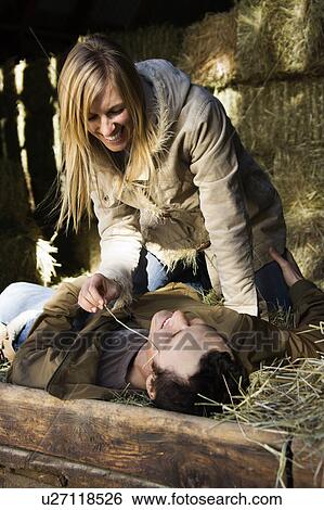 Woman playfully leaning over man lying in hay View Large Photo Image Stock Photograph - Woman playfully leaning over man lying in hay. Fotosearch