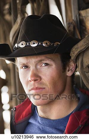 Stock Photograph - Young adult male wearing cowboy hat looking at viewer. Fotosearch