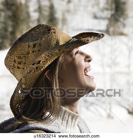 Picture - Young woman laughing wearing cowboy hat outdoors in winter. Fotosearch