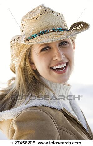 Stock Photography - Young woman looking at viewer wearing cowboy hat. Fotosearch