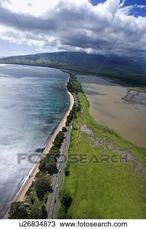 Stock Image - Aerial of road following Maui, Hawaii coastline with beach. Fotosearch