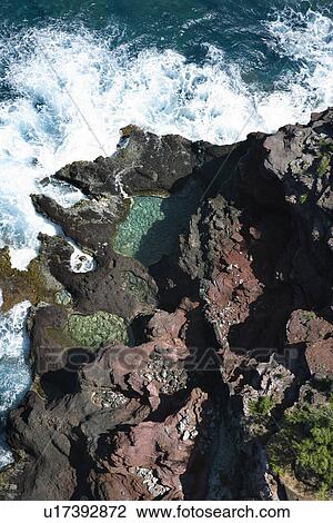 Stock Image - Aerial view of waves crashing on rocks in Maui, Hawaii.. Fotosearch