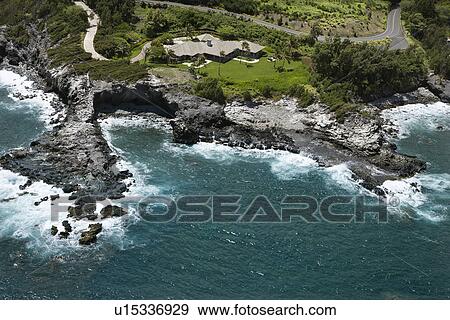 Stock Photo - Rocky coastline on Maui, Hawaii with rooftop view of building and road. Fotosearch
