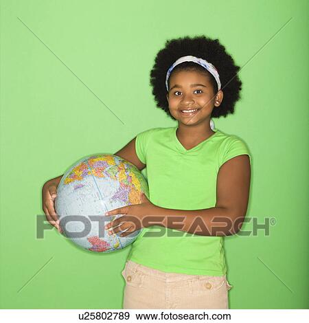 Stock Photo - African American girl holding globe at hip and smiling at viewer.. Fotosearch