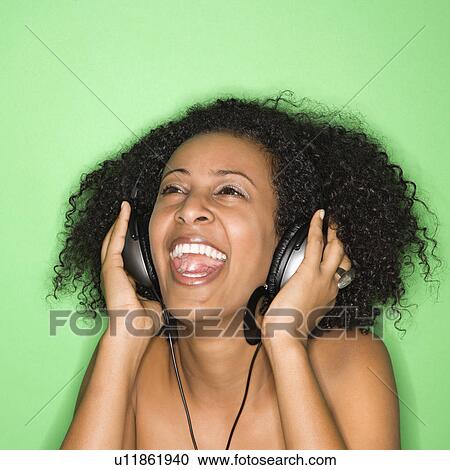 African-American woman listening to music through headphones. View Large Photo Image Stock Image - African-American woman listening to music through headphones.. Fotosearch