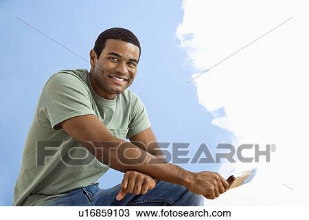 African American young man sitting next to half-painted wall with paintbrush. View Large Photo Image Stock Image - African American young man sitting next to half-painted wall with paintbrush.. Fotosearch