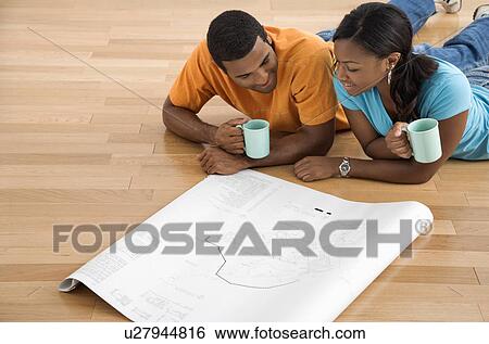 Couple lying on floor looking at architectural blueprints View Large Photo Image Stock Photograph - Couple lying on floor looking at architectural blueprints. Fotosearch