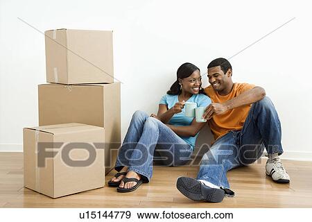 Couple sitting on floor next to moving boxes relaxing View Large Photo Image Stock Photo - Couple sitting on floor next to moving boxes relaxing. Fotosearch