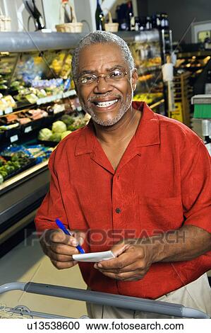 Stock Image - Man in grocery store holding shopping list. Fotosearch