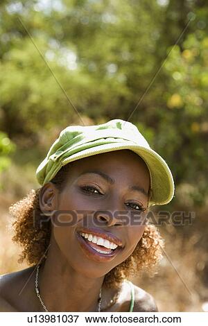 Stock Photo - MId-adult Black female wearing cap and making eye contact.. Fotosearch