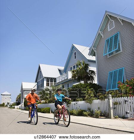 Middle aged African American couple bicycling down street next to homes and fence. View Large Photo Image Stock Photo - Middle aged African American couple bicycling down street next to homes and fence.. Fotosearch