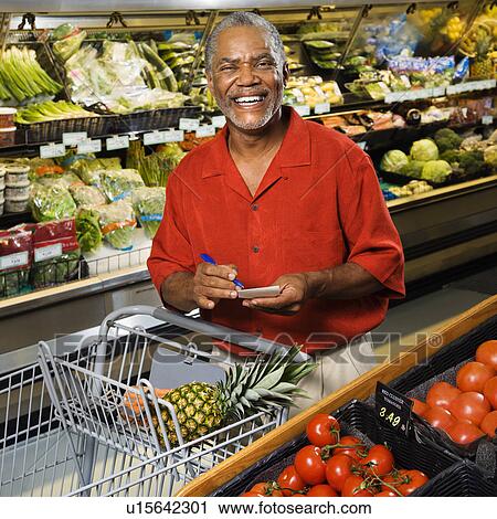 Middle aged African American man in grocery store holding shopping list and smiling at viewer. View Large Photo Image Stock Image - Middle aged African American man in grocery store holding shopping list and smiling at viewer.. Fotosearch