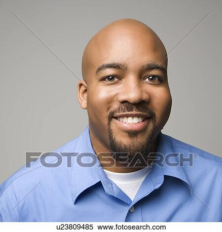 Stock Photography - Portrait of African American man smiling against gray background.. Fotosearch