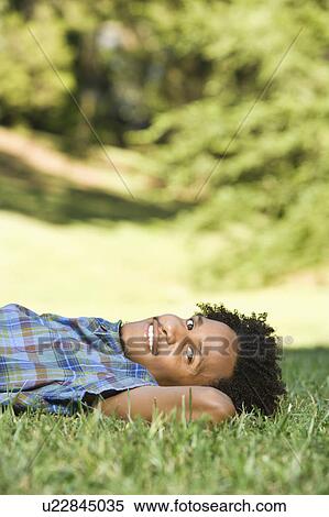 Portrait of man lying in grass in park smiling. View Large Photo Image Stock Photography - Portrait of man lying in grass in park smiling.. Fotosearch