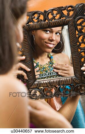Woman smiling at reflection in mirror wearing necklace View Large Photo Image Stock Photo - Woman smiling at reflection in mirror wearing necklace. Fotosearch