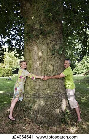 Couple hugging a tree View Large Photo Image Stock Image - Couple hugging a tree. Fotosearch