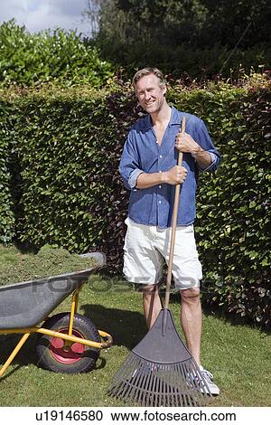 Man holding rake by wheelbarrow View Large Photo Image Stock Image - Man holding rake by wheelbarrow. Fotosearch