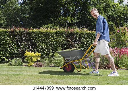 Stock Photo - Man walking with wheelbarrow. Fotosearch