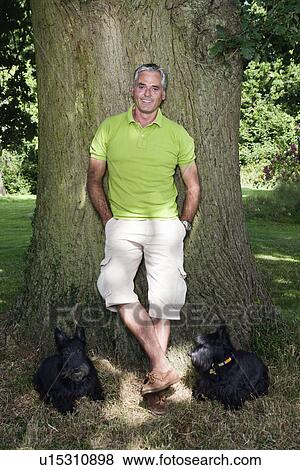 Stock Photo - Portrait of middle age man with his dogs. Fotosearch