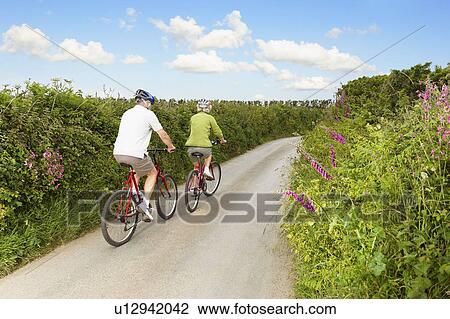 Senior couple cycling up country lane View Large Photo Image Stock Image - Senior couple cycling up country lane. Fotosearch