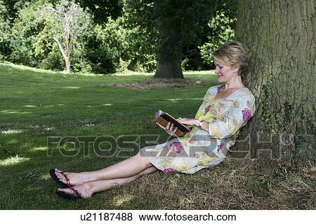 Women leaning a tree reading a book View Large Photo Image Stock Photo - Women leaning a tree reading a book. Fotosearch