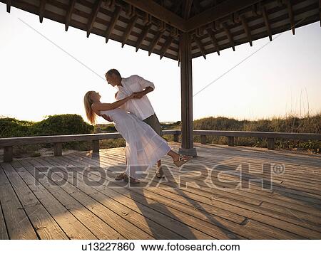 Stock Image - Couple dancing under gazebo at the beach. Fotosearch
