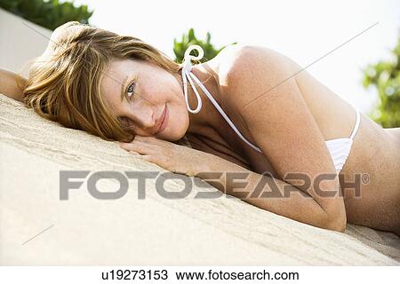 Stock Image - Female lying in sand wearing bikini. Fotosearch