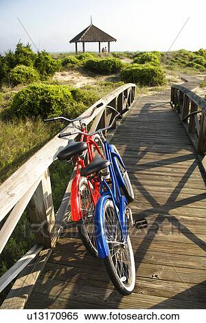 Stock Photography - Image of red and blue bike leaning against railing of boardwalk. . Fotosearch