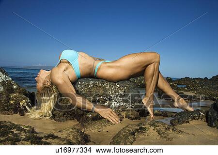 Pretty Caucasian mid adult woman bodybuilder in bikini lying on rock on beach. View Large Photo Image Picture - Pretty Caucasian mid adult woman bodybuilder in bikini lying on rock on beach.. Fotosearch