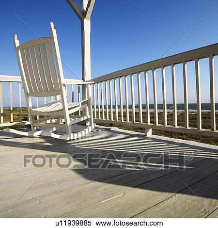 Stock Photography - Rocking chair on porch with railing overlooking beach at Bald Head Island, North Carolina.. Fotosearch